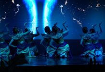 Dekranasda Bali Fashion Day Bangun Ekosistem Sandang Sekelompok penari perempuan mengenakan kostum bernuansa hijau dan emas tampil di atas panggung dengan latar layar LED bercahaya biru dalam acara Dekranasda Bali Fashion Day di Denpasar.
