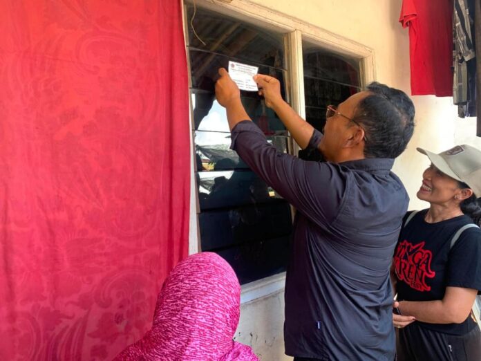 Petugas Dinas Sosial Buleleng menempel stiker di rumah penerima bantuan sosial di Kelurahan Penarukan.