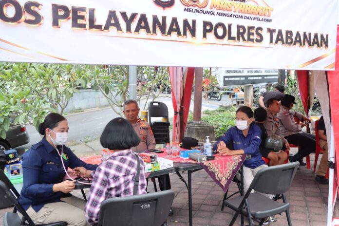 Personel Polres Tabanan melayani warga di tenda Pos Pelayanan dekat SPBU Sanggulan saat antrean BBM memanjang hingga sekitar satu kilometer untuk sepeda motor.