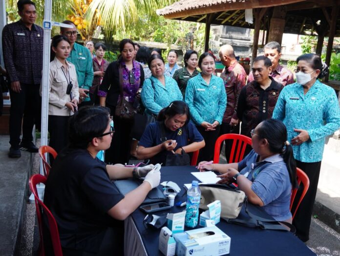 Ny Putri Koster menyerahkan bantuan dalam aksi sosial TP PKK Bali di Karangasem